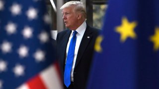 American President Donald Trump seen in between the flags of the U.S. and the European Union.