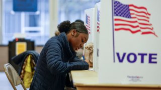 A woman casts her ballot during early voting for the US general election at a polling station at Ottawa Hills High School in Grand Rapids, Michigan, on November 3, 2024. 