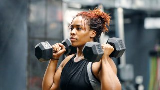 Wasit up image of a fit, young woman working out with hand weights in a fitness gym.