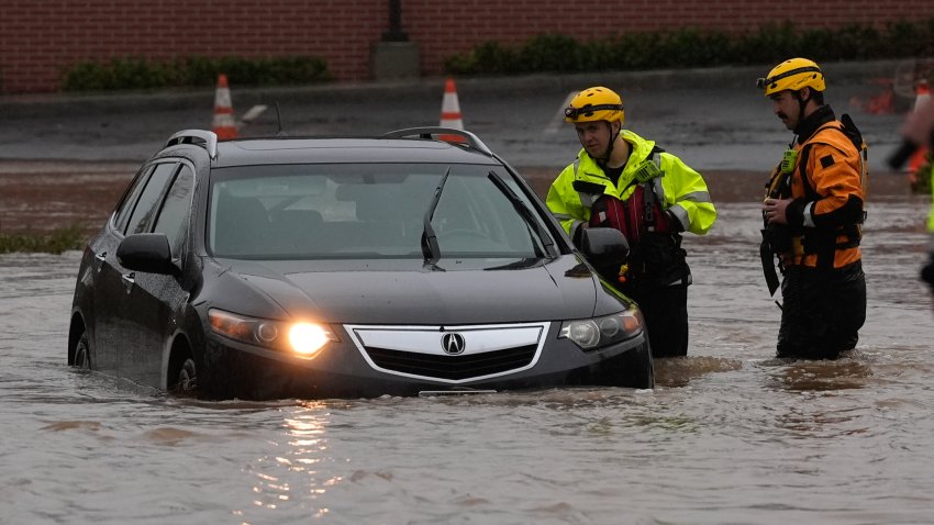 Santa Rosa firefighters attend to a submerged car in a flooded street.