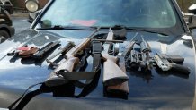 Police showed a sampling of guns, parts and accessories collected at a Guns to Gardens event by laying them out on the hood of a patrol car.