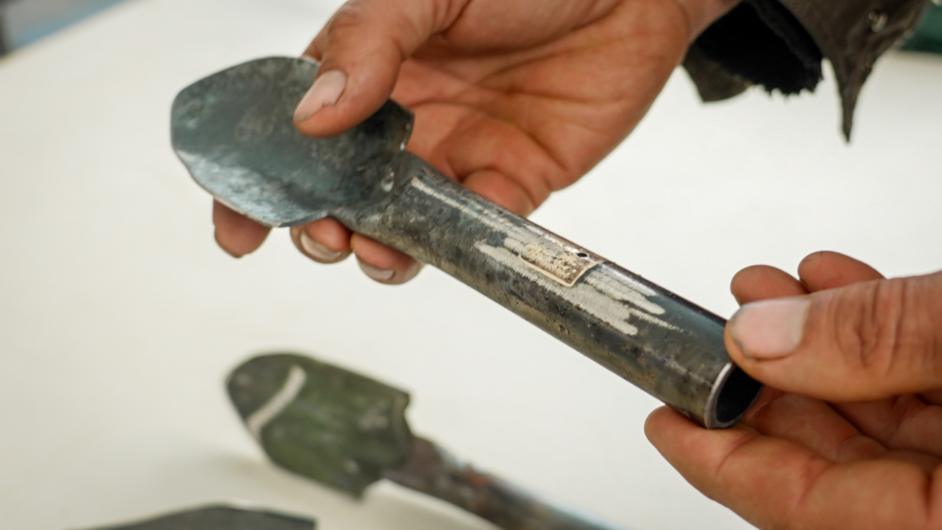 A small garden spade with markings and engraving on its handle that resemble those on the barrel of a gun