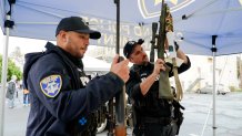 Two police officers examining long guns