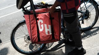 An app-based delivery worker waits outside of a restaurant in New York City on July 7, 2023.