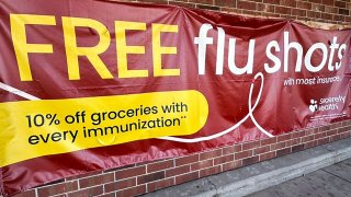 FILE – A sign for flu vaccination is displayed outside of a grocery store in Glenview, Ill., Thursday, Feb. 15, 2024.