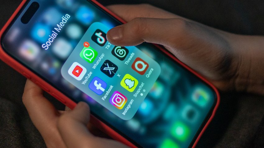 A teenager holding a phone with social media apps.