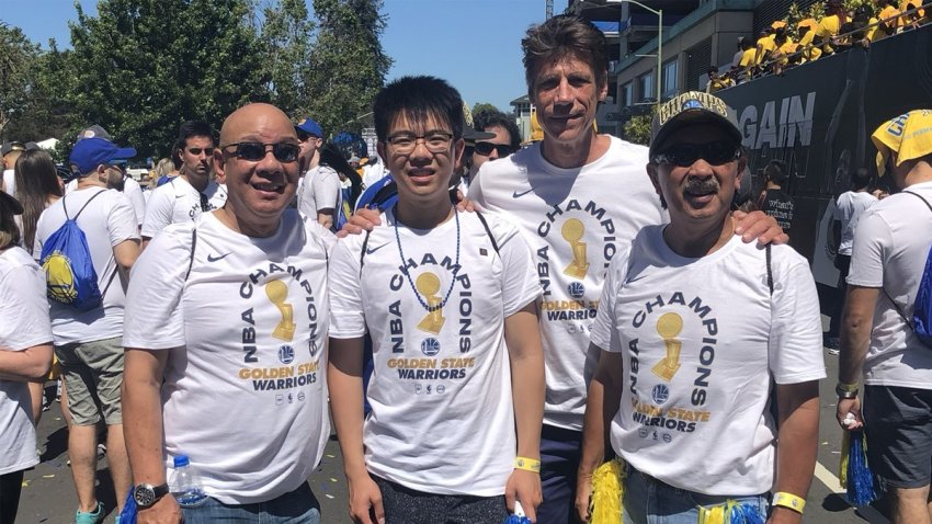 Golden State Warriors Season Ticket Holder representative Don Moffett poses for a photo with the Wong family at an NBA championship parade.