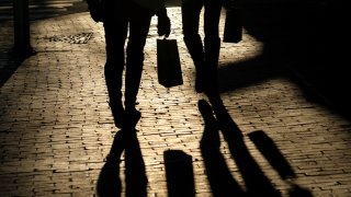 Shoppers cast shadows as they carry their bags along the waterfront in Portland, Maine, U.S, December 26, 2024. 
