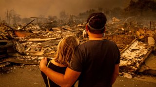 Megan Mantia, left, and her boyfriend Thomas, only first game given, return to Mantia’s fire-damaged home after the Eaton Fire swept through the area, Wednesday, Jan. 8, 2025, in Altadena, Calif. 