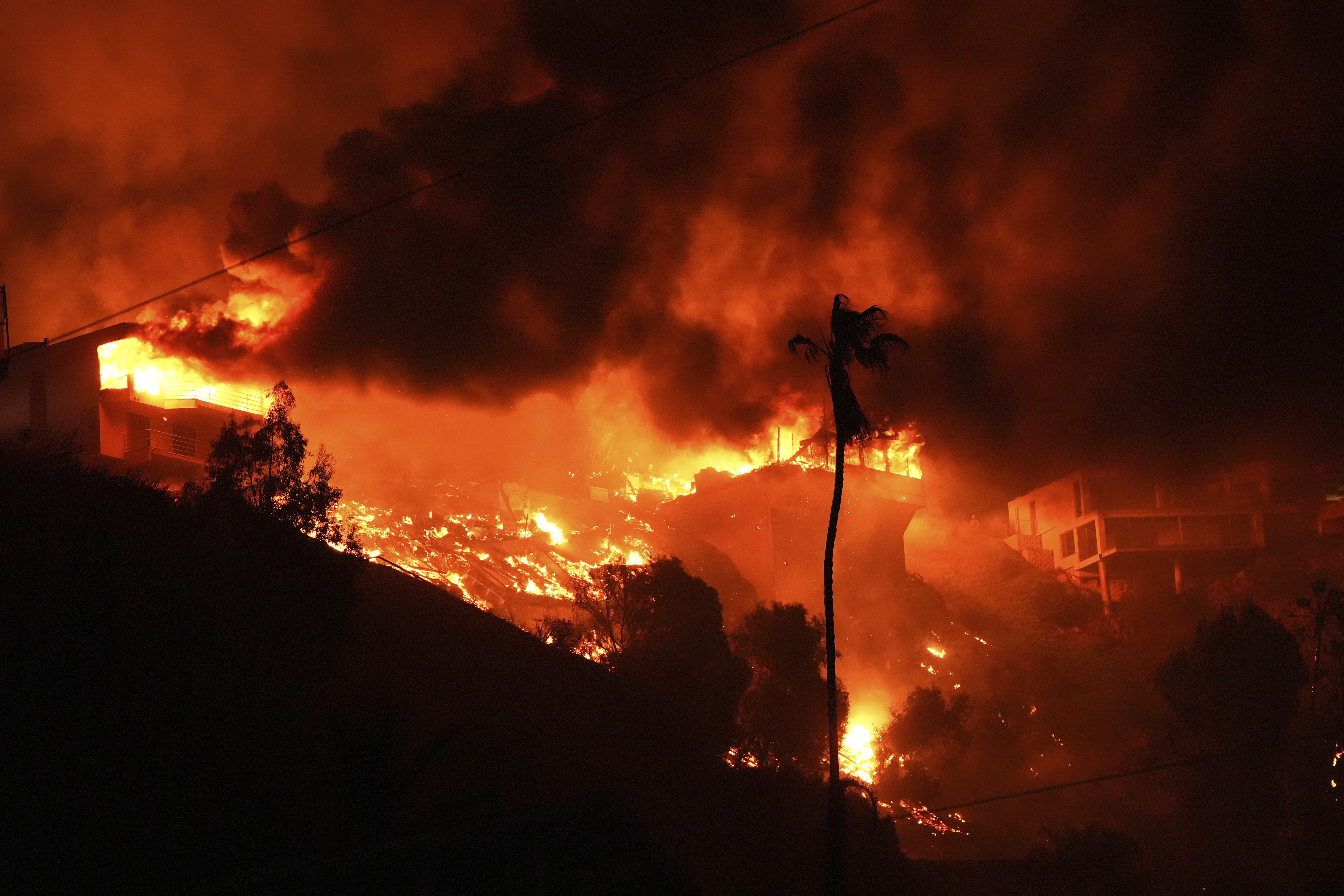 The Palisades Fire burns homes on a hilltop in the Pacific Palisades neighborhood of Los Angeles, Wednesday, Jan. 8, 2025.