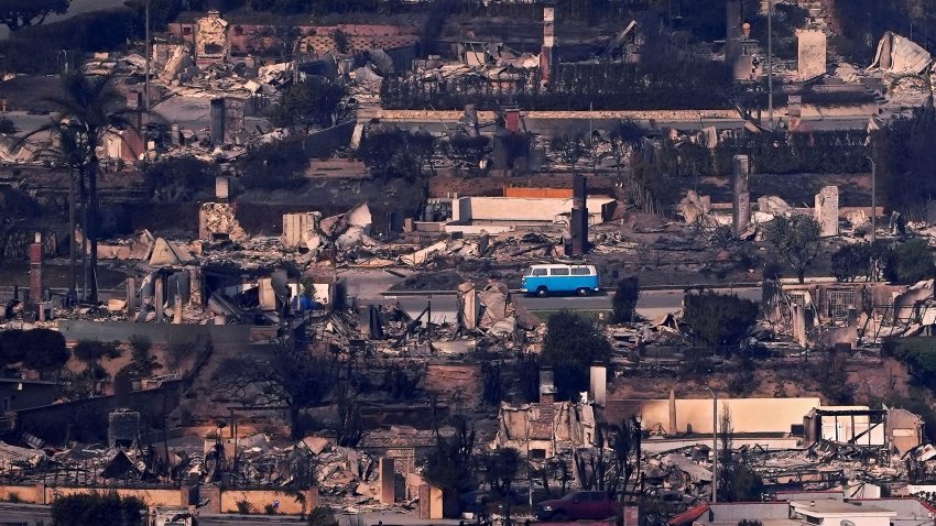 A VW van sits among burned out homes