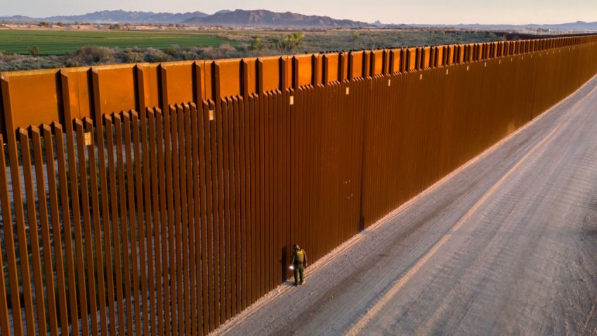 In an aerial view, a U.S. Border Patrol agent searches for immigrant footprints while looking through the U.S.-Mexico border fence on March 9, 2024 in Yuma, Arizona.