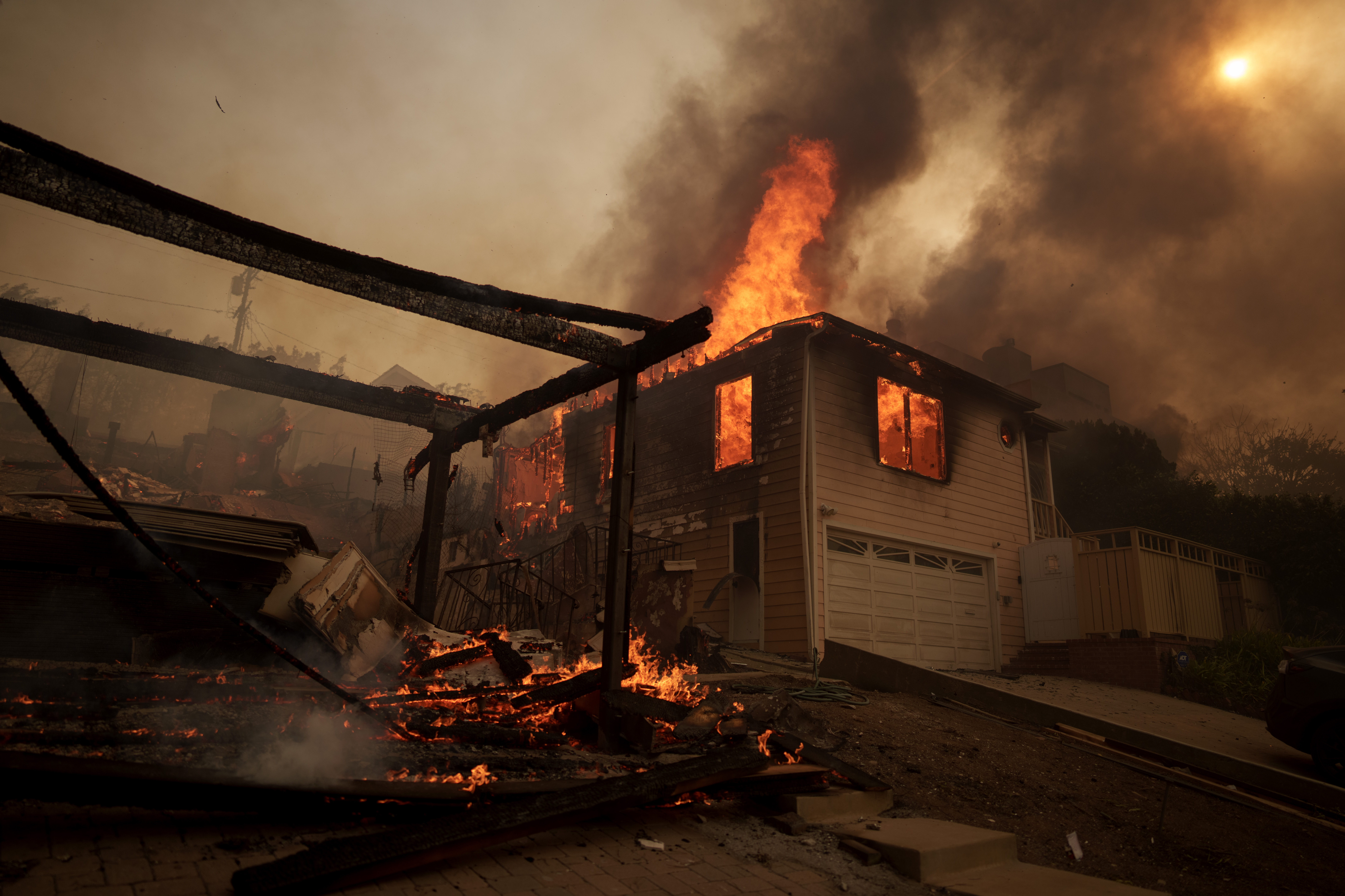 Flames from the Palisades Fire burn a home.