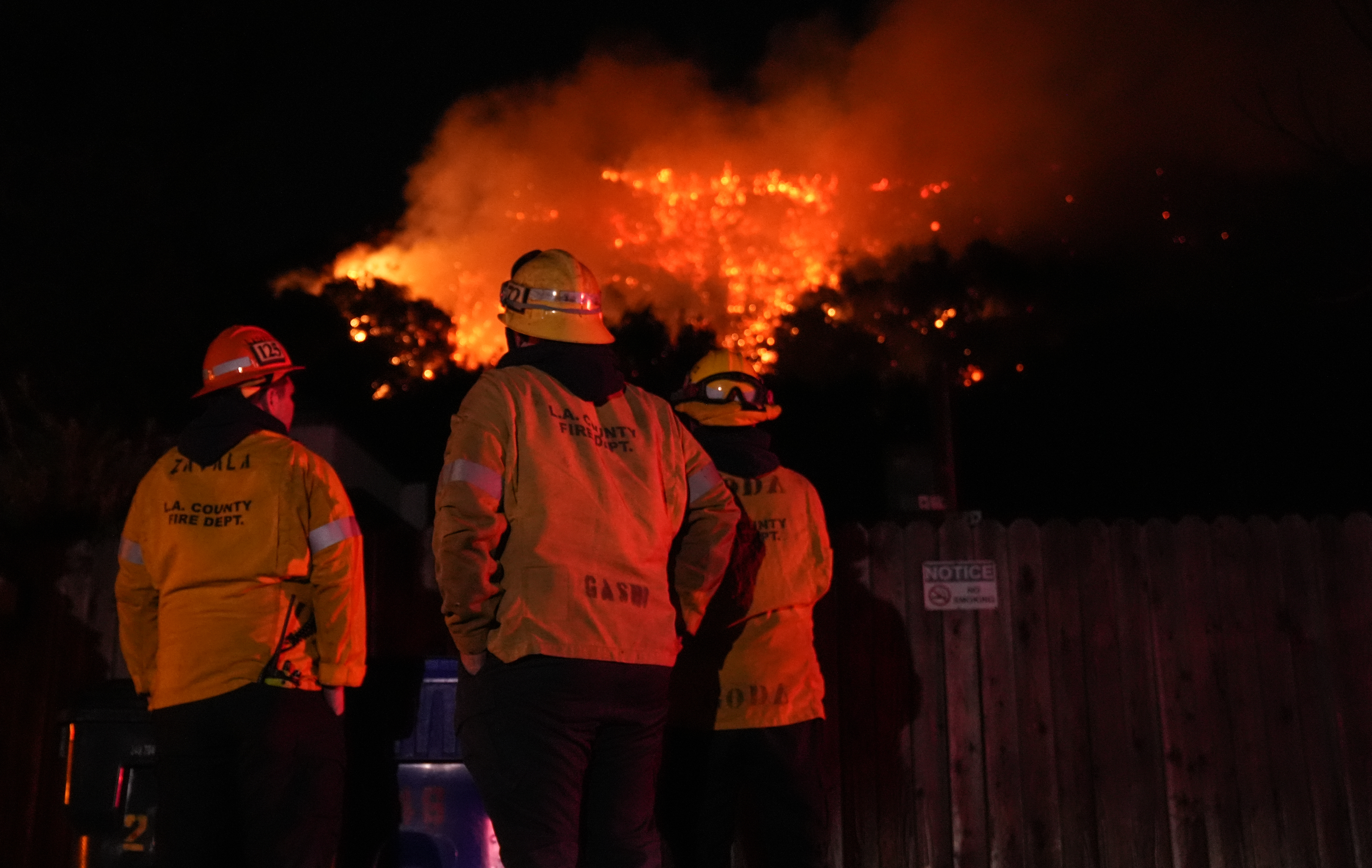 Firefighters from the Los Angeles County Fire Department stand vigilant as they battle wildfires in Los Angeles while several blazes continue to tear through the region on January 10, 2025.