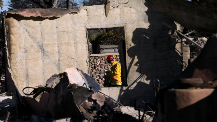 CalFire Deputy State Fire Marshall Michelle Knight is framed by what is left of a fire ravaged home from the Eaton fire while doing damage inspection in Altadena on January 15, 2025.