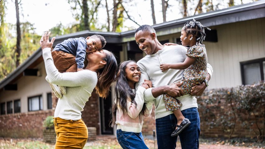 Portrait of family with young children in front of suburban home