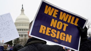 A person displays a sign as labor union activists rally in support of federal workers during a protest, with the U.S. Capitol in the background on Capitol Hill in Washington, U.S., Feb. 11, 2025. 