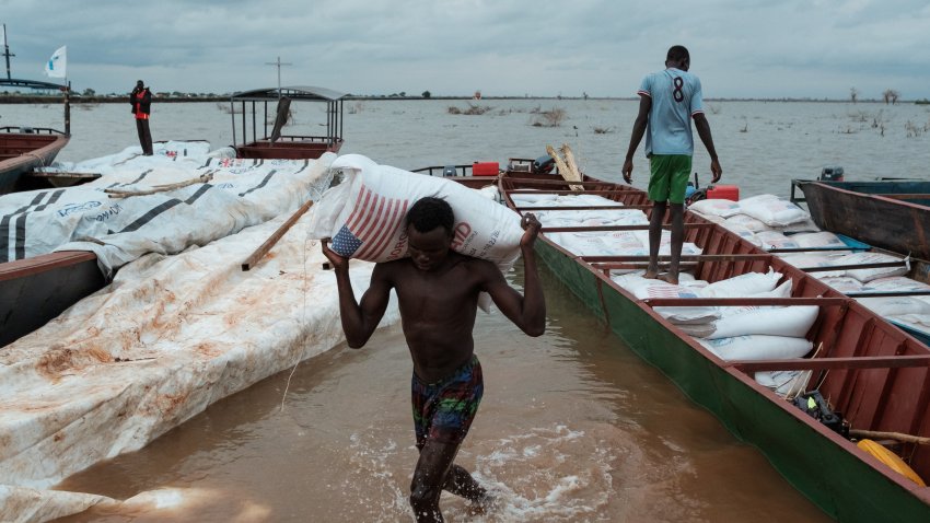 A young man carries a USAID bag of Sorghum in Bentiu, South Sudan, in 2023.