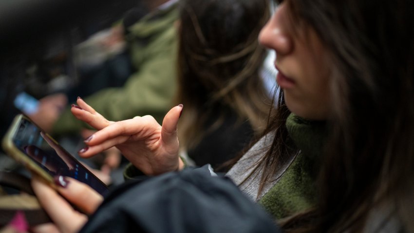 A subway passenger reads her iPhone