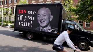 A video protest sign on a truck paid for by the Patriotic Millionaires drives past a mansion owned by Amazon founder Jeff Bezos as part of a federal tax filing day protest to demand he pay his fair share of taxes, in Washington, May 17, 2021.