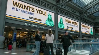 People walk past digital billboards at the Moynihan Train Hall displaying a new initiative from New York Governor Kathy Hochul titled ‘New York Wants You’, a program designed to recruit and employ displaced federal workers across New York State, in New York, U.S., March 3, 2025. 