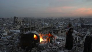 Palestinians Ali Marouf and his mother Aisha cook on fire on the roof of their destroyed house by the Israeli army’s air and ground offensive in Jabaliya, Gaza Strip, on Monday, March 17, 2025. (AP Photo/Jehad Alshrafi)