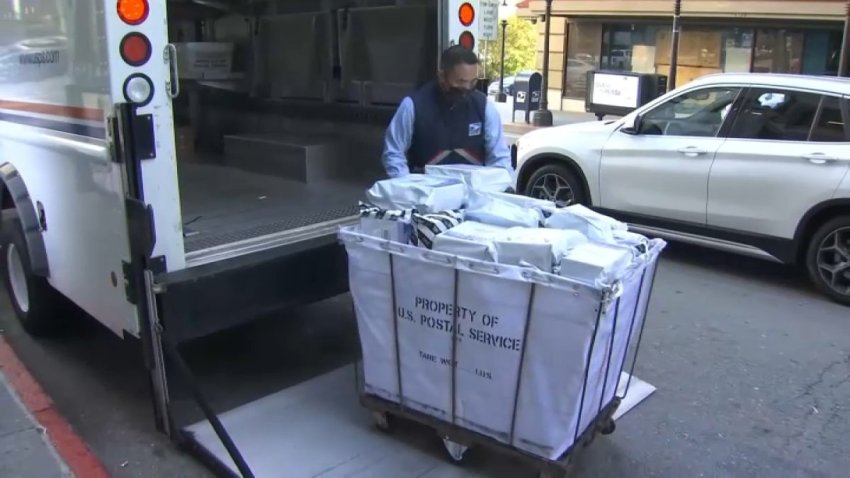 A postal worker loads mail into his truck.