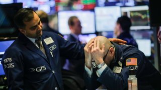 A trader is comforted by a coworker as they work on the floor of the New York Stock Exchange, March 1, 2018.