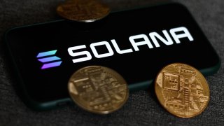 The Solana logo on a phone screen and representation of cryptocurrencies are seen in this photo taken in Krakow, Poland, Aug. 21, 2021.