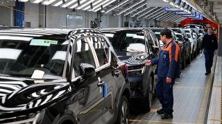 Workers inspect cars at the end of the production line of the Volvo factory in Ghent on April 25, 2025.