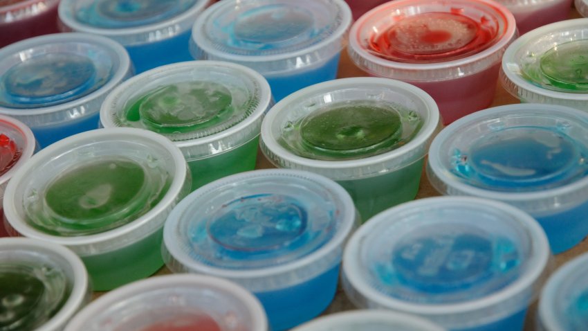 Jello shots in plastic cups with lids on.  Served at parties and bars as a fun food, typically containing liquor such as vodka,tequila or whiskey.