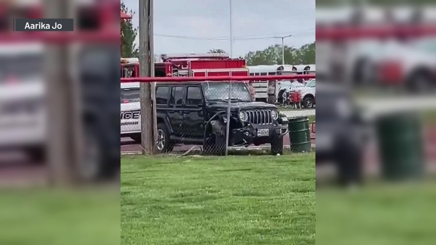 A black SUV is seen crashed against a chain-link fence.