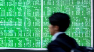 A man walks past an electronic board showing the Nikkei 225 index on the Tokyo Stock Exchange along a street in Tokyo on April 7, 2025.