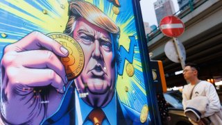 People walk past an advertisement feature Donald Trump with Bitcoin in Hong Kong.