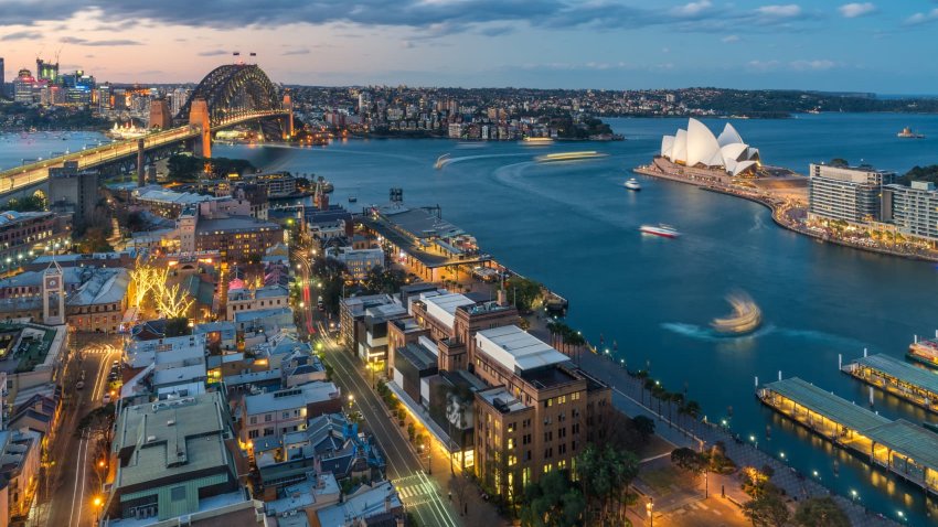 Waterfront city skyline of Sydney city downtown at night with bright illumination of modern architectural landmarks in Sydney, Australia.