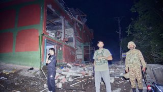 Security force officials stand outside a damaged building at a site of a suspected Indian missile attack near Muzaffarabad, the capital of Pakistan controlled Kashmir, in Wednesday, May 7, 2025.