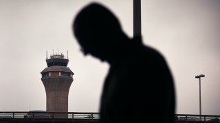 A man stands outside Terminal C with the airport control tower in the background at Newark Liberty International Airport, on May 6, 2025 in Newark, New Jersey.