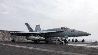Flight deck crew members prepare to catapult an F/A-18 Super Hornet fighter jet aboard the USS Dwight D. Eisenhower (CVN 69) aircraft carrier in March 2024.