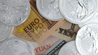 In this photo illustration, banknotes of the Euro, Japanese Yen, Chinese Yuan and U.S. dollar bill are placed under one-ounce silver bullion coins arranged in Katwijk, Netherlands, on Feb. 20, 2021.
