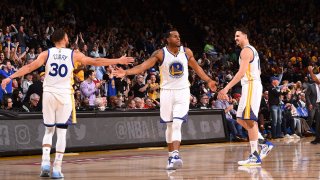 Andre Iguodala, #9; Stephen Curry, #30; and Klay Thompson, #11, of the Golden State Warriors high-five one another during the game against the Boston Celtics at the Oakland Arena in Oakland, California, on March 8, 2017.