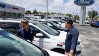 Salesman Walter Silva (R) helps Alexis Lechanet shop for a Ford vehicle at Metro Ford on May 6, 2025 in Miami, Florida.
