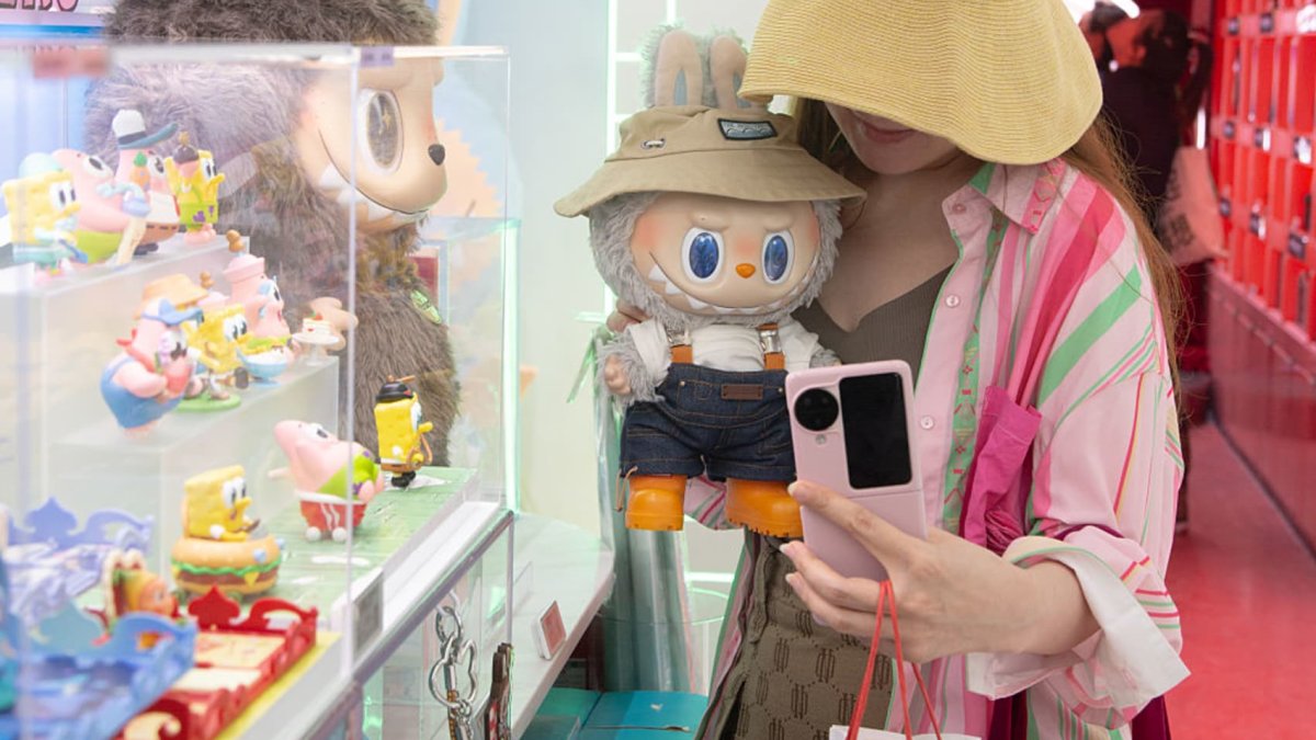 一位女士在上海的Pop Mart商店與Labubu娃娃合影