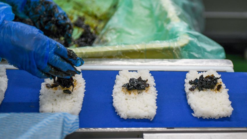 A worker puts konbu seaweed on rice at a rice ball production line at the processing factory of Fuji Foods Co., in Funabashi, Chiba, Japan, on Friday, Jan. 26, 2024.