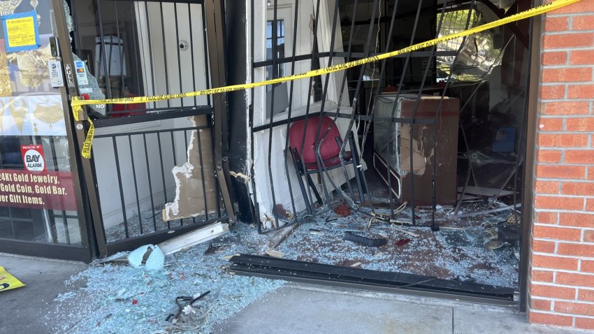 The glass front of a store has been smashed and is draped across with crime scene tape.