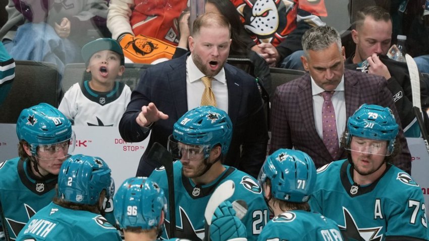 Oct 11, 2025; San Jose, California, USA; San Jose Sharks head coach Ryan Warsofsky (center) talks with players during the third period against the Anaheim Ducks at SAP Center at San Jose. Mandatory Credit: Darren Yamashita-Imagn Images