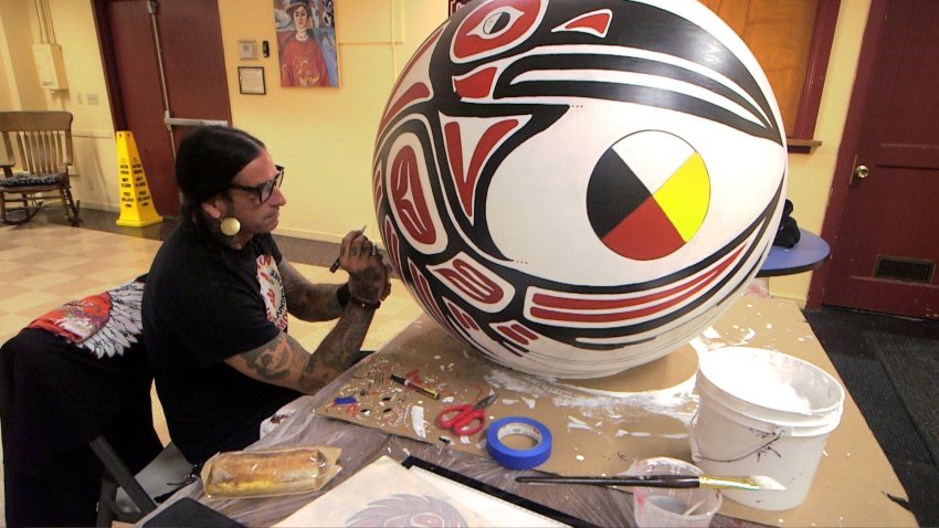 Indigenous artist Maize Black paints traditional tribal designs on a sphere.